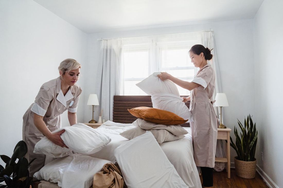 Two hotel housekeepers changing bedding